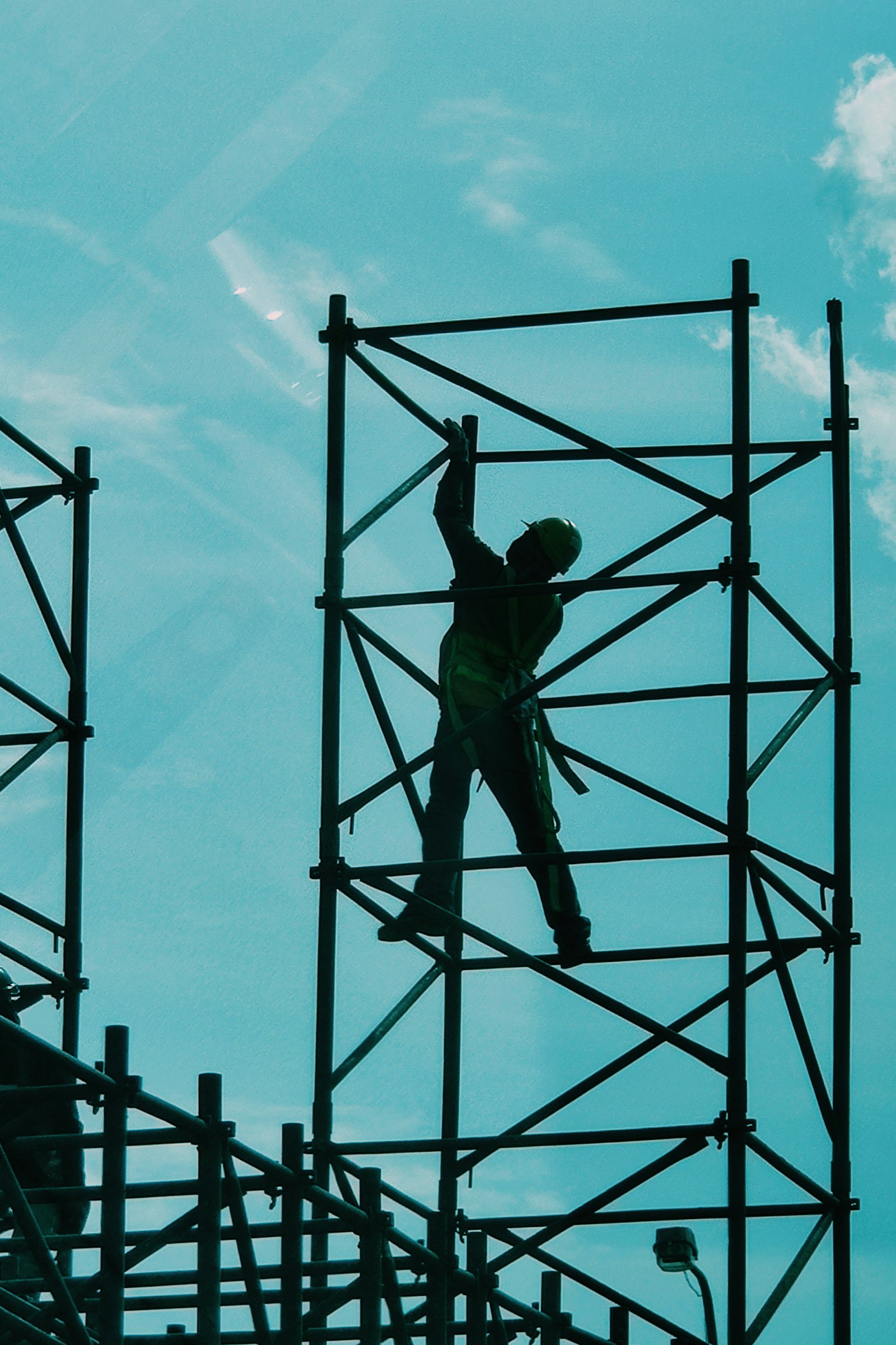A worker climbing a scaffold tower against the sky