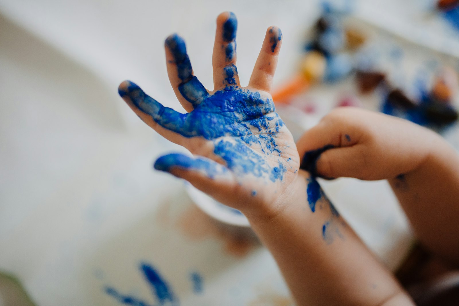 A child's hand covered in blue finger paint
