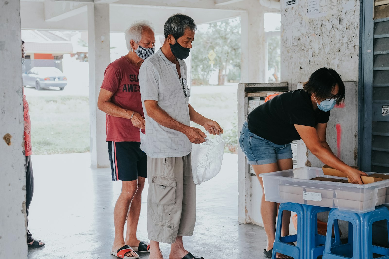 A volunteer handing a bag over a crate to people at a community hall
