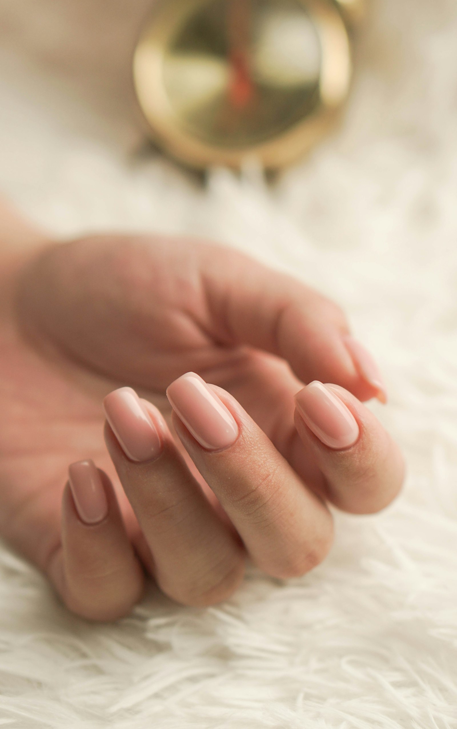 Light pink manicured nails on a soft white surface