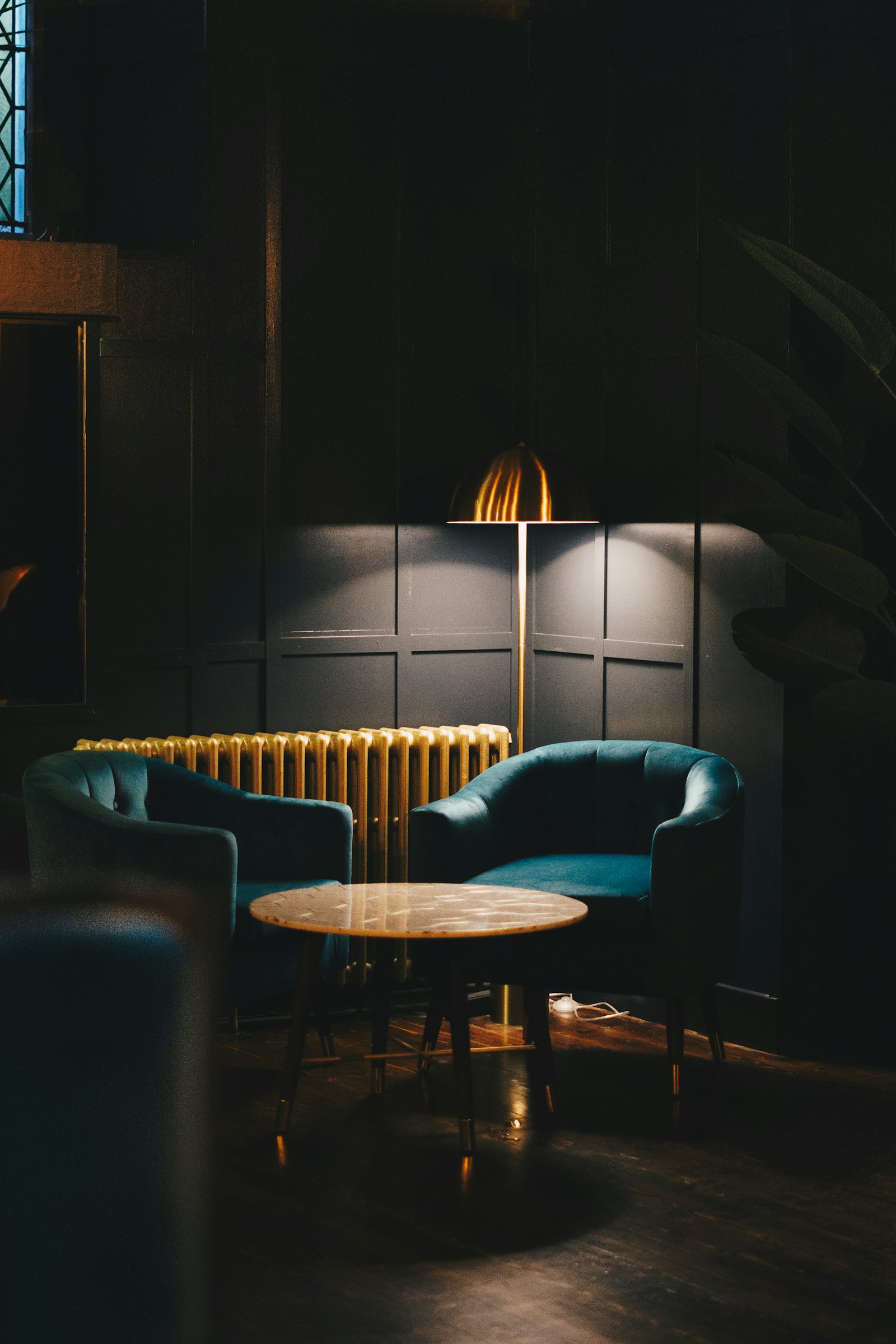 A panelled lounge corner with teal velvet armchairs