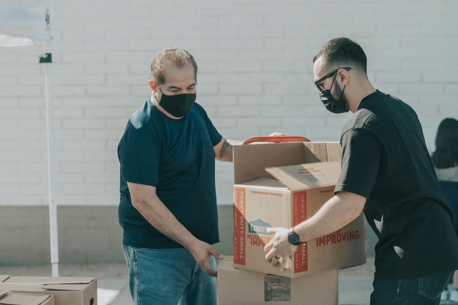 Two volunteers carrying a donation box together outside