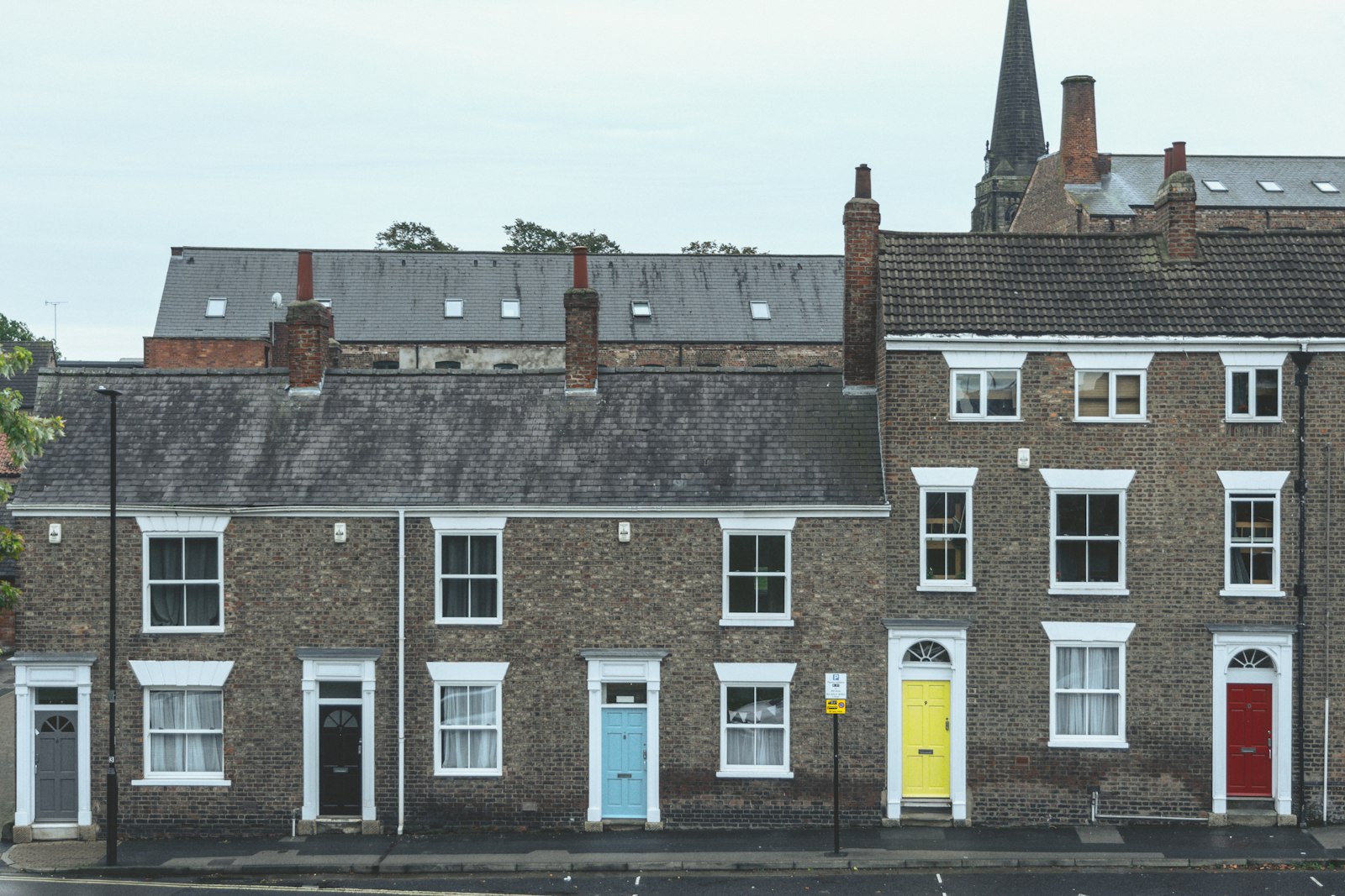 A brick terrace with painted doors and a spire behind