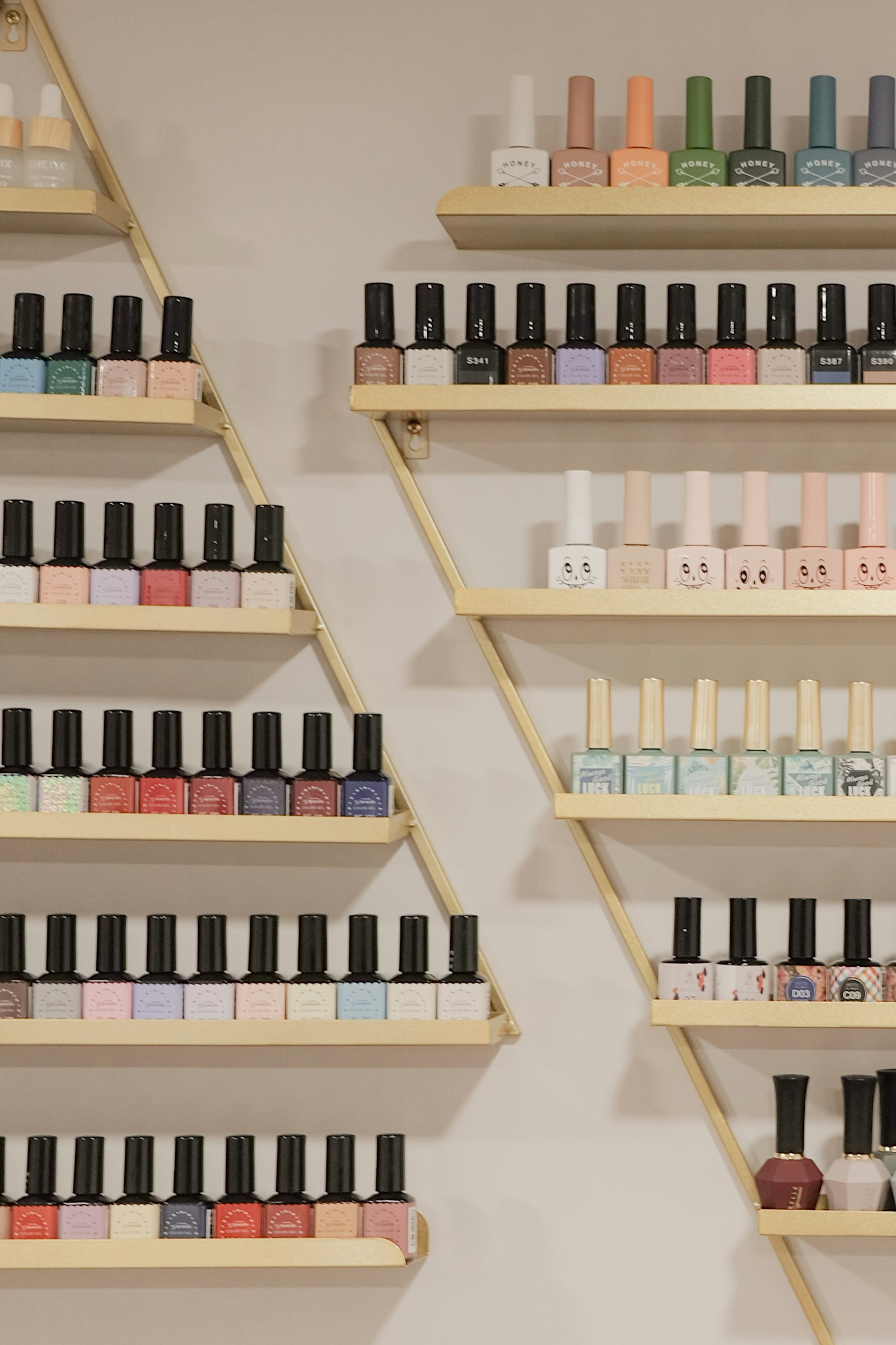 Gold wall shelves lined with rows of coloured nail polish bottles