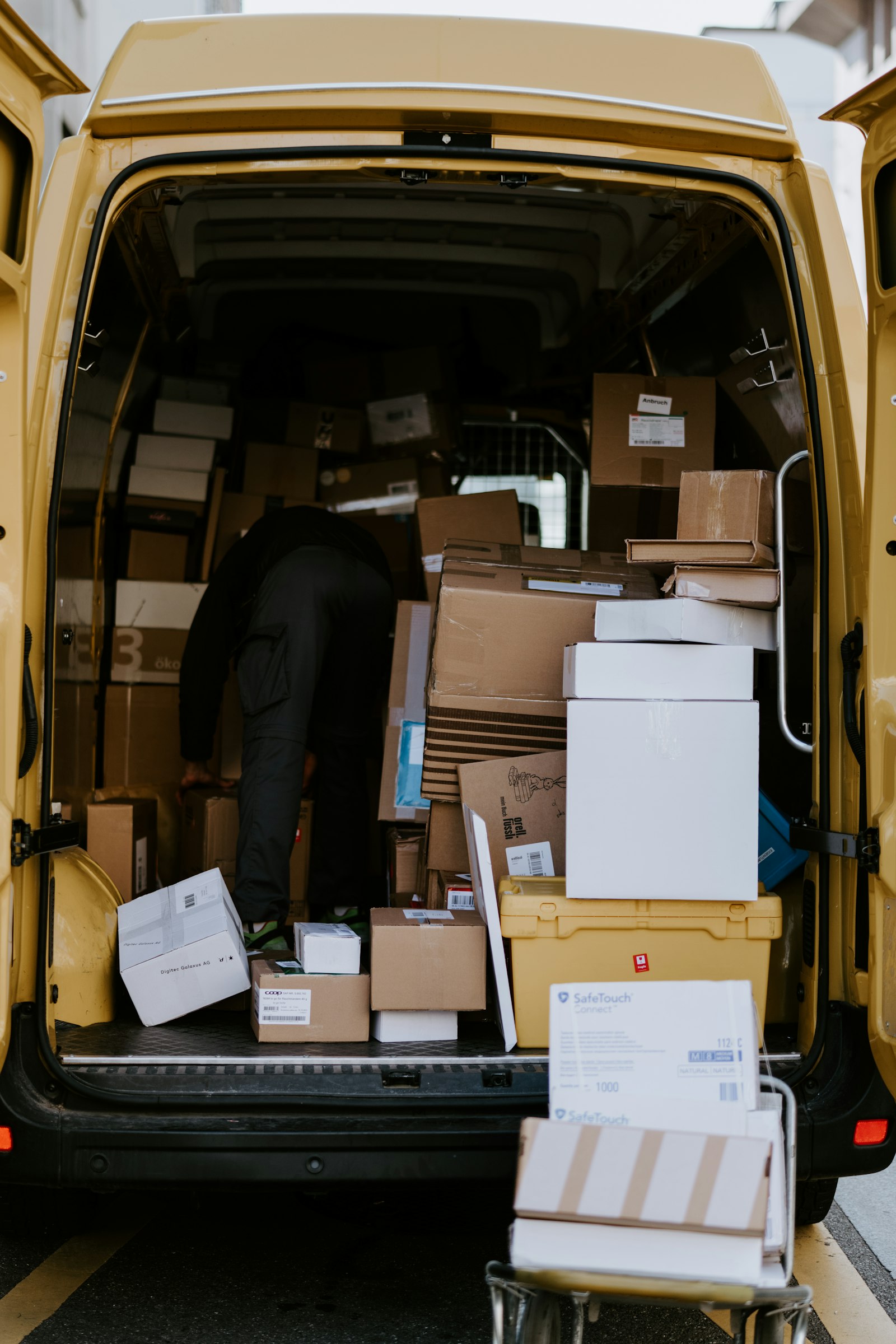 A person loading cardboard boxes into the back of a van
