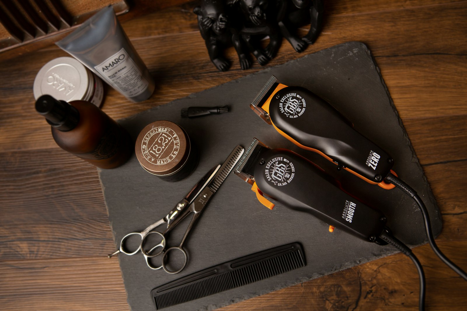 Clippers, scissors, a comb and grooming pots on slate