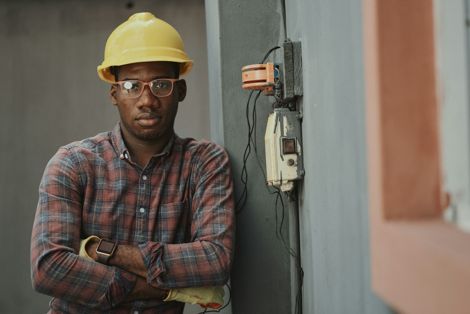 The electrician standing beside a half-wired wall socket with his arms folded