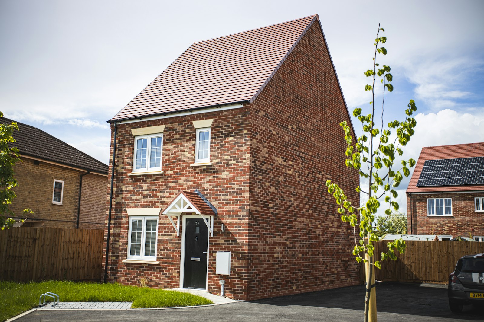 A new-build red-brick detached house with a young tree