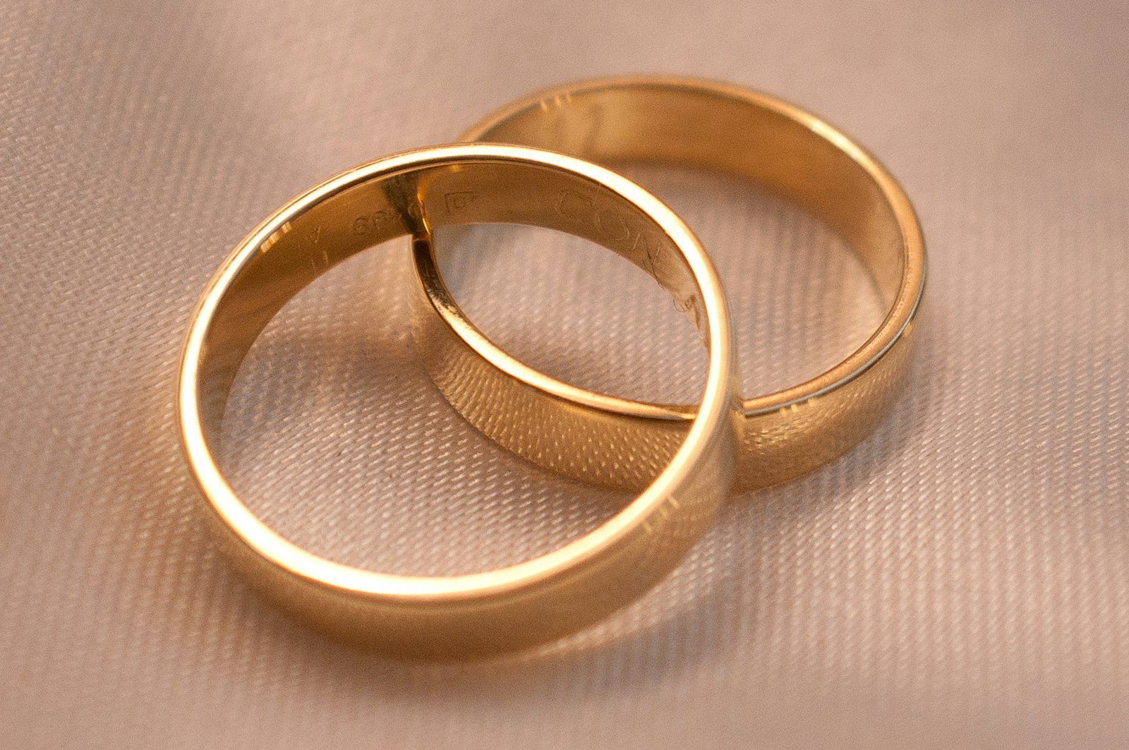 Two gold wedding bands on cream fabric
