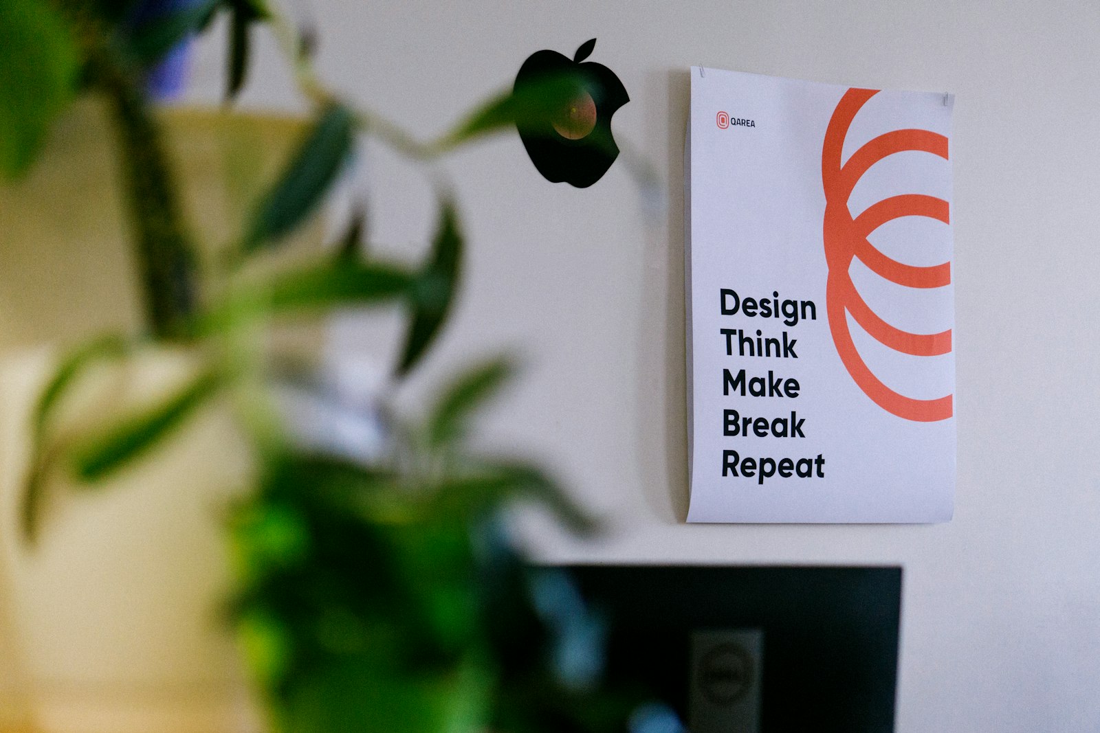 A card reading Design, Think, Make, Break, Repeat pinned beside a plant