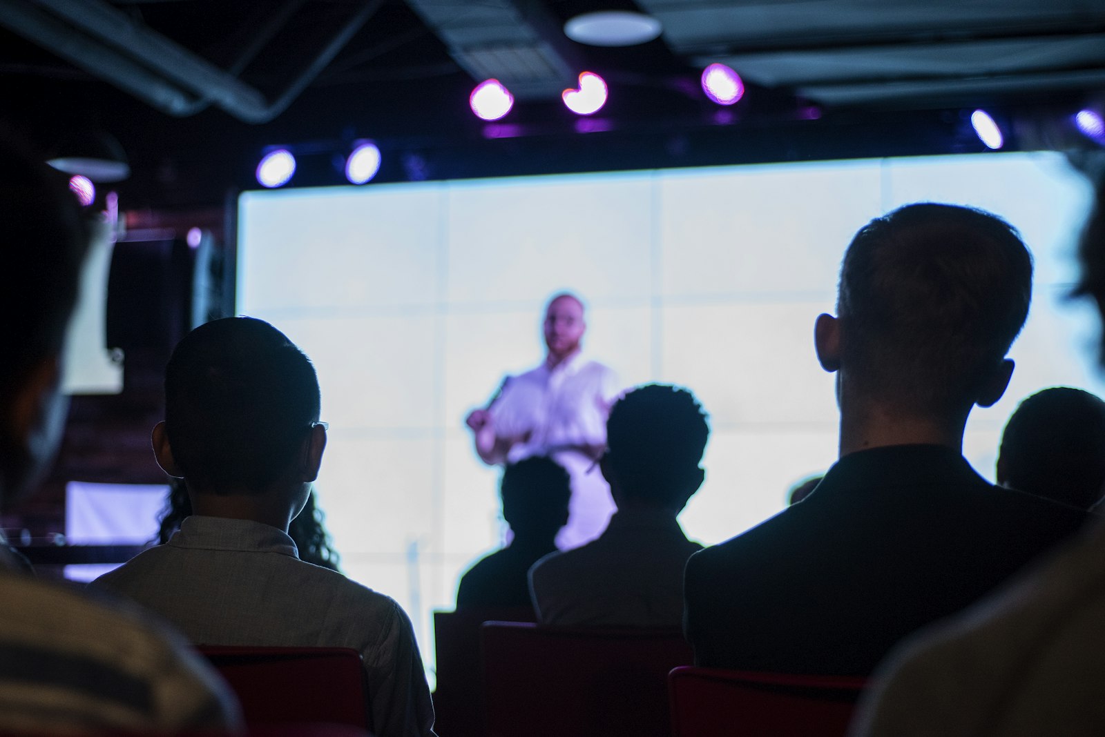 Audience silhouettes in front of a bright screen