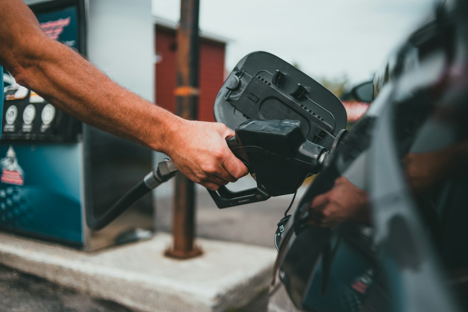A hand holding a fuel nozzle at a petrol pump