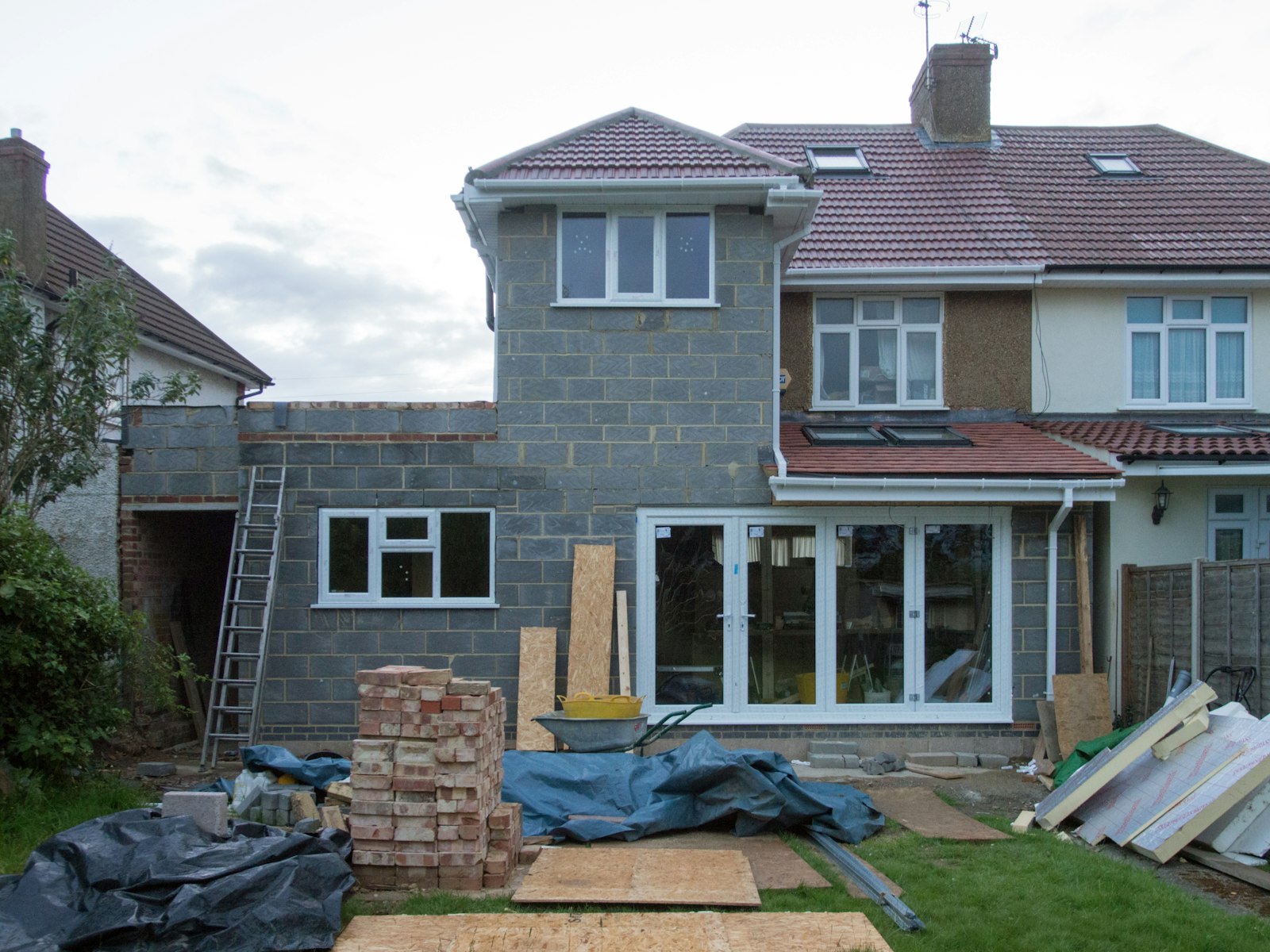A single-storey rear extension in block-work on a semi-detached house, a ladder against the wall