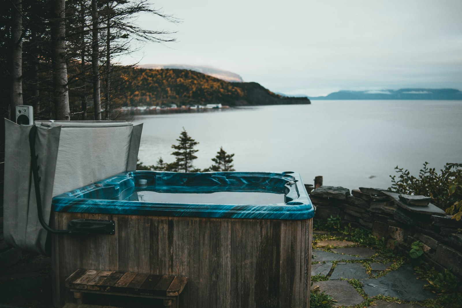 A wooden hot tub on a deck above a wooded bay