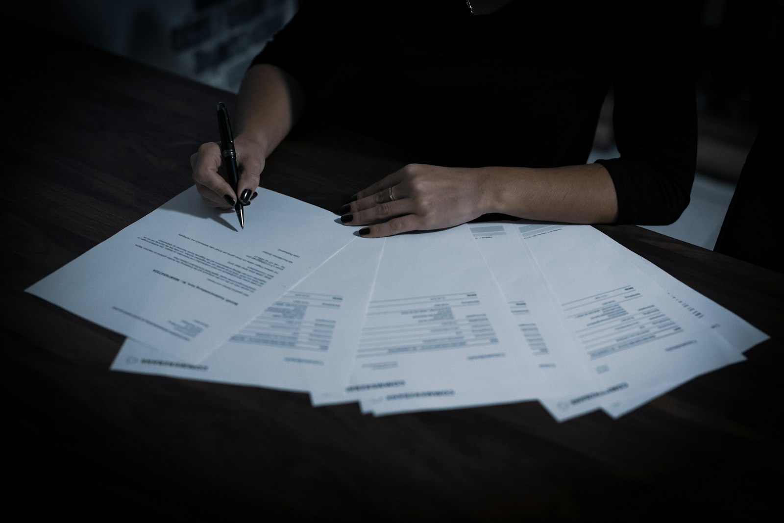 A woman working through papers spread across a table