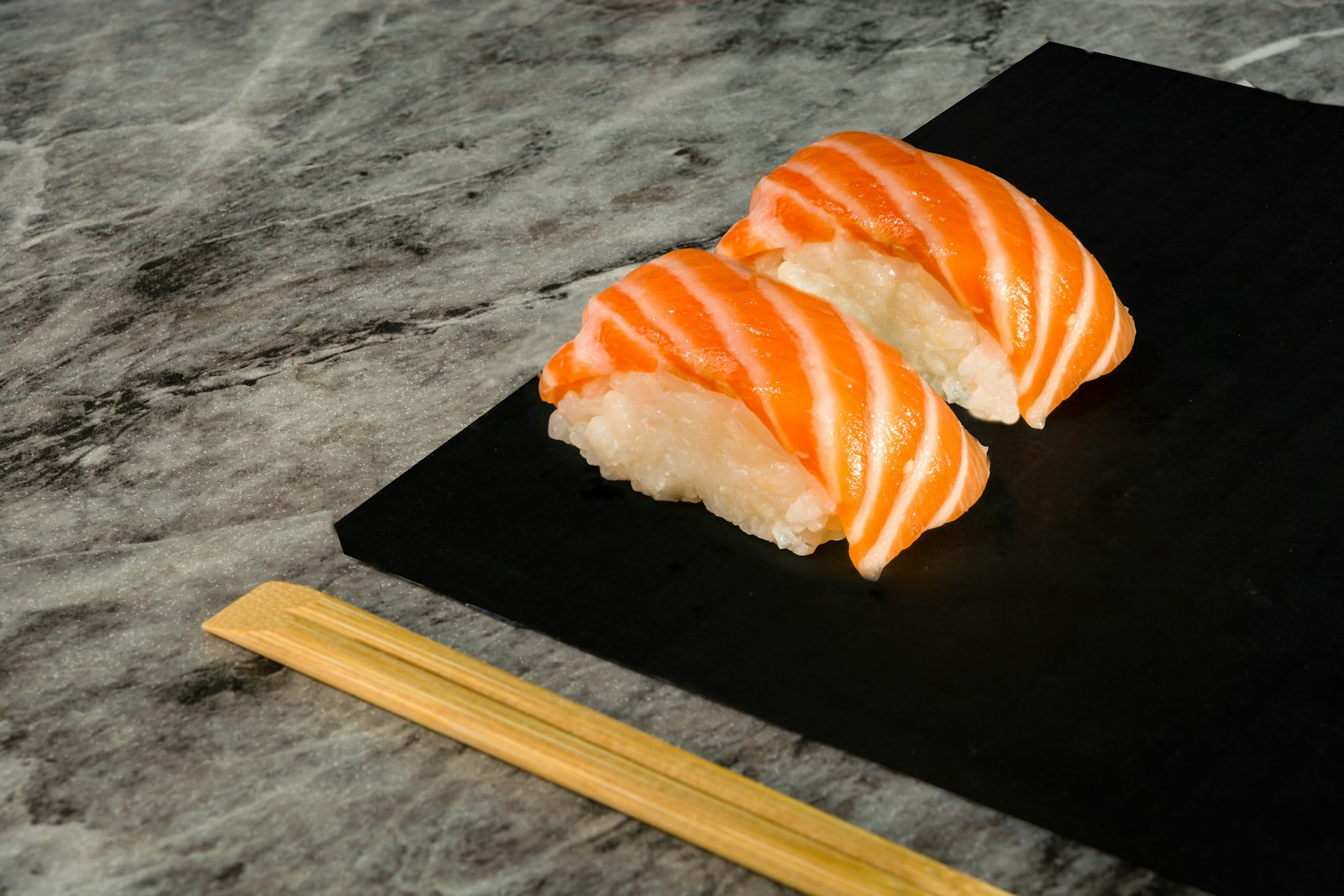 Two salmon nigiri on slate