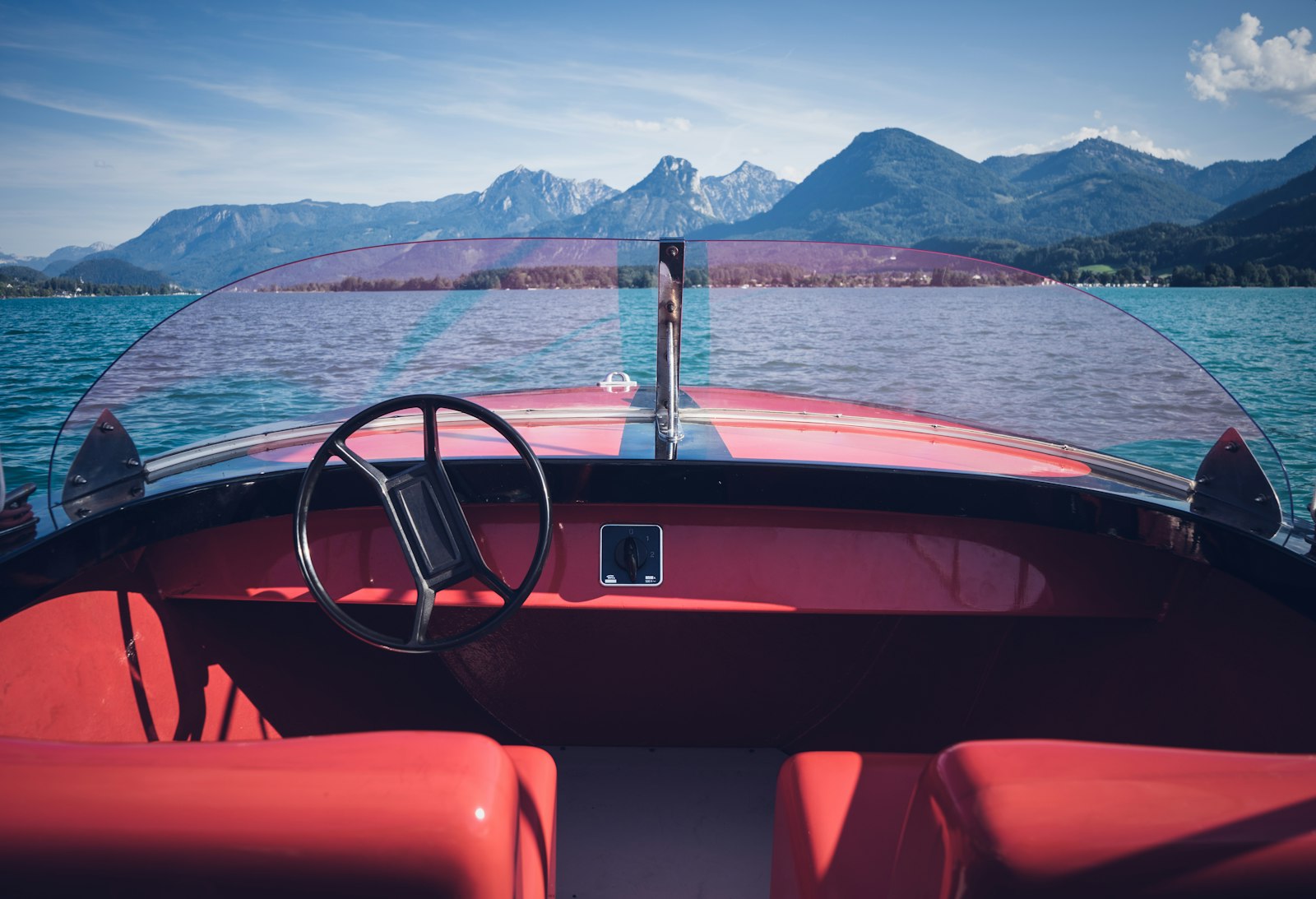 The helm and windscreen of a small motorboat on a lake