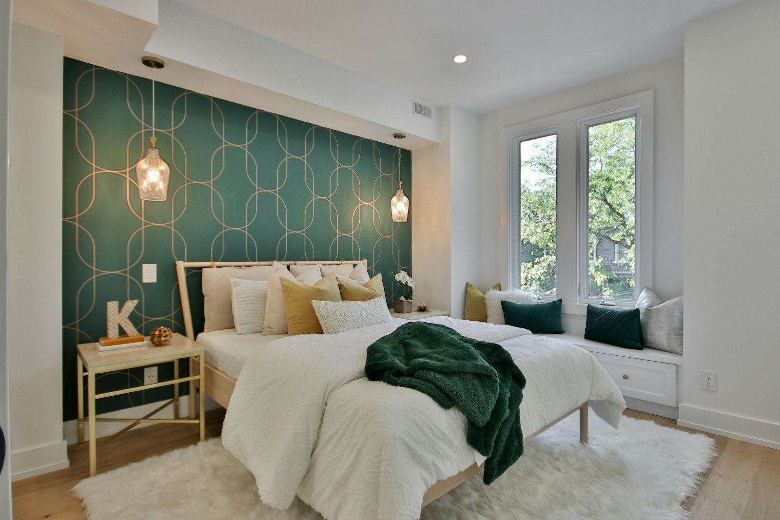 A show-home bedroom with a dark green wall and a window seat