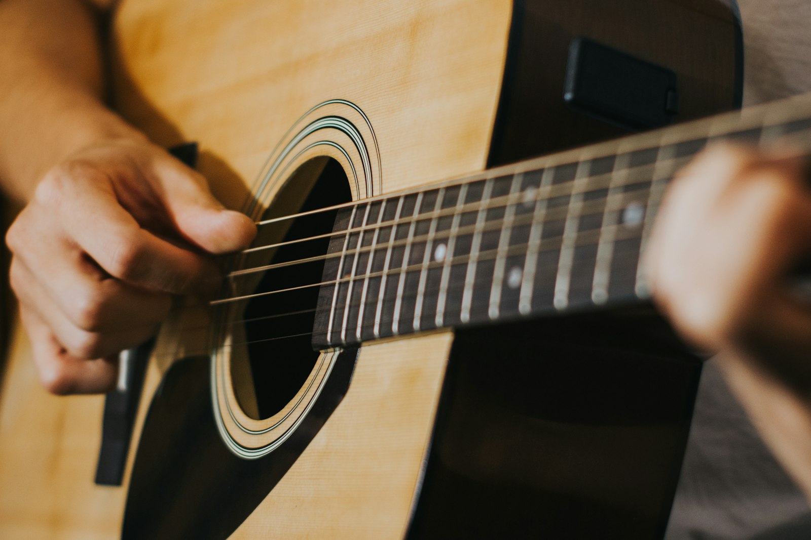 Fingers on the strings of an acoustic guitar, close up