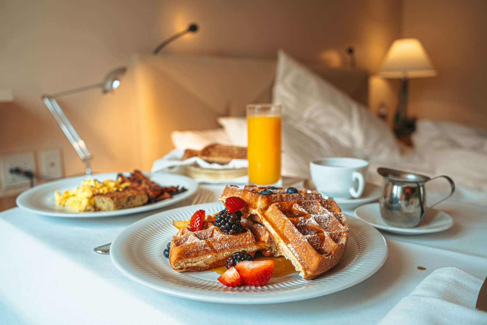 Breakfast in bed on a tray with waffles, eggs, juice and coffee