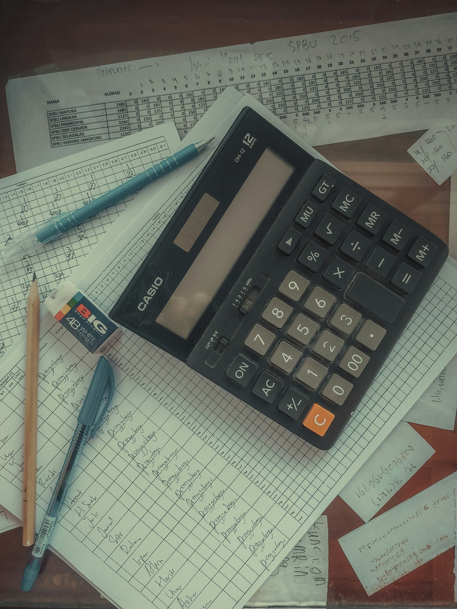 A calculator and pen on a ledger sheet of handwritten figures