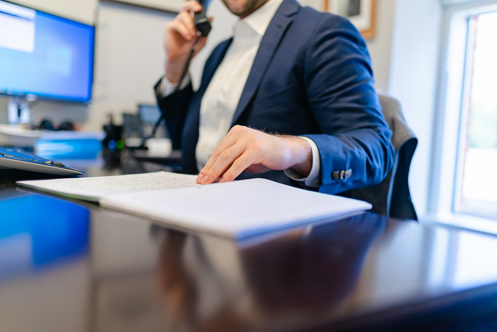 A broker on the phone at his desk with papers
