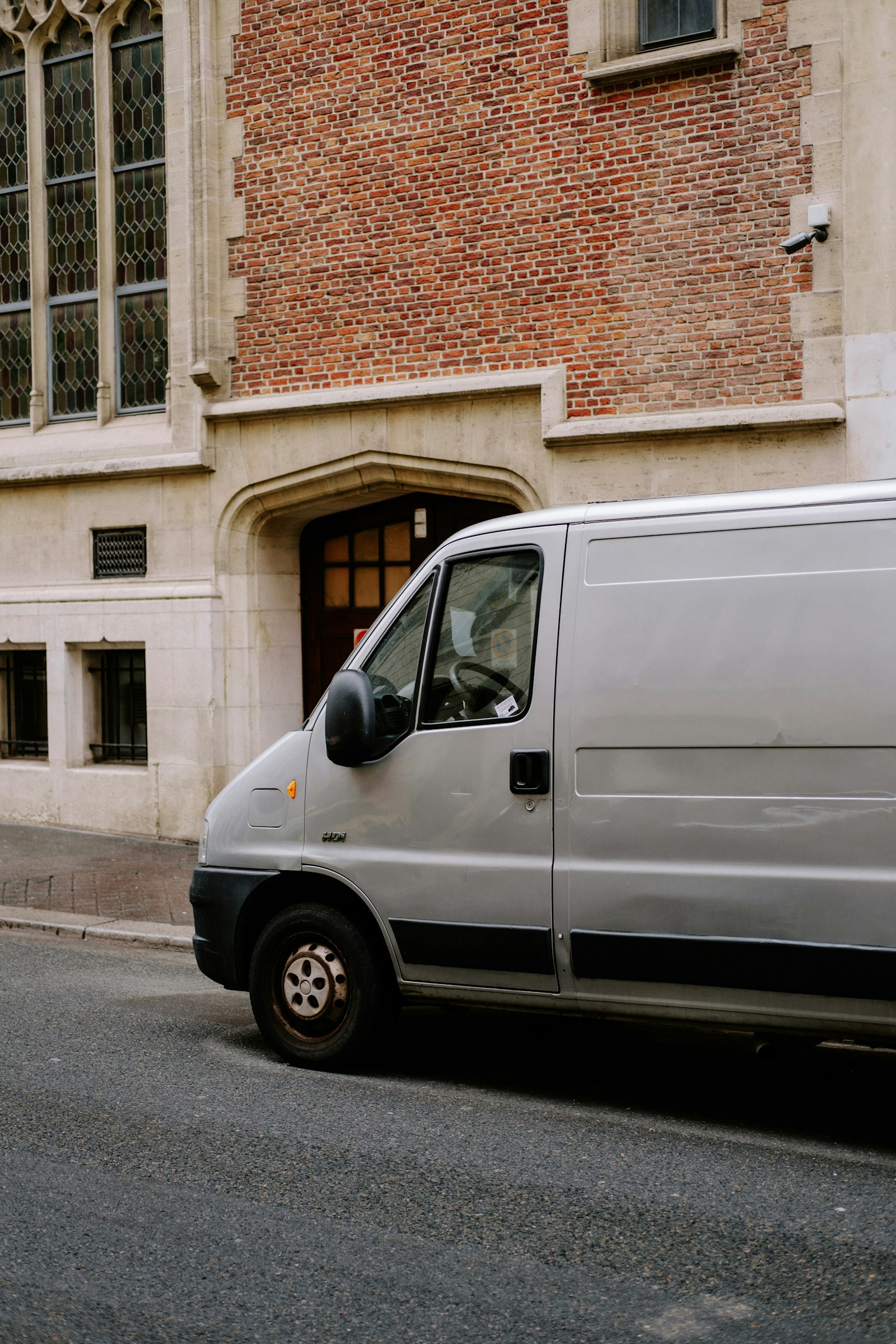 A large white van parked beside a brick and stone building
