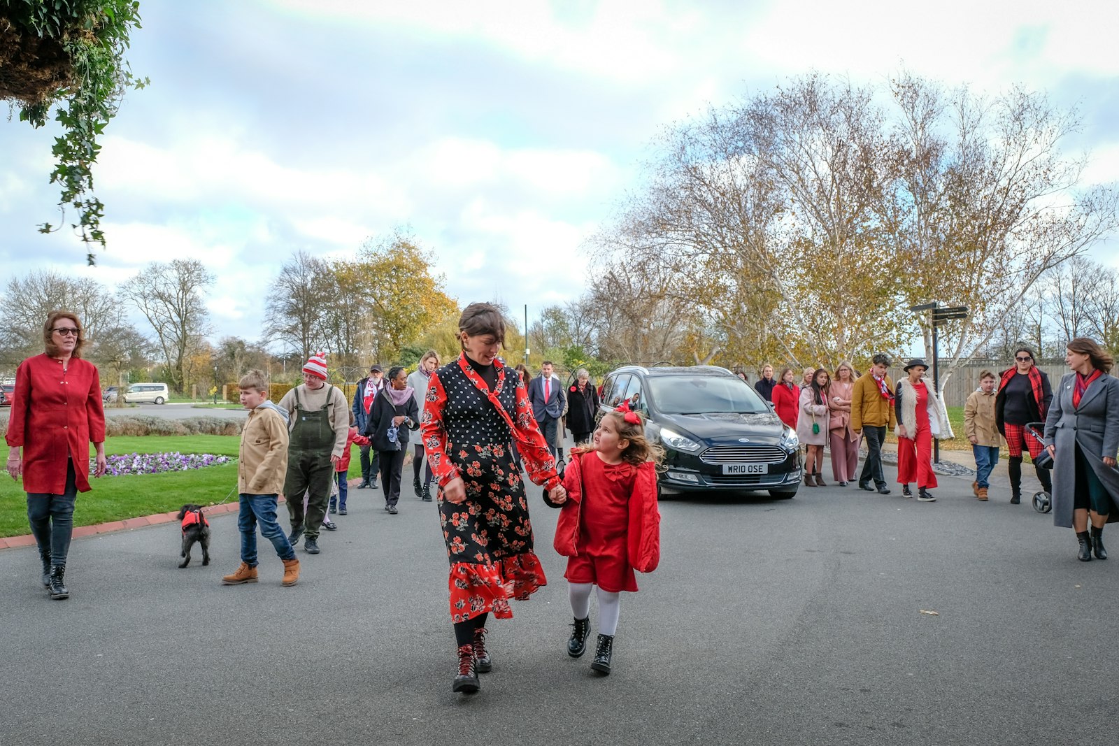 Families in red walking together through an autumn park