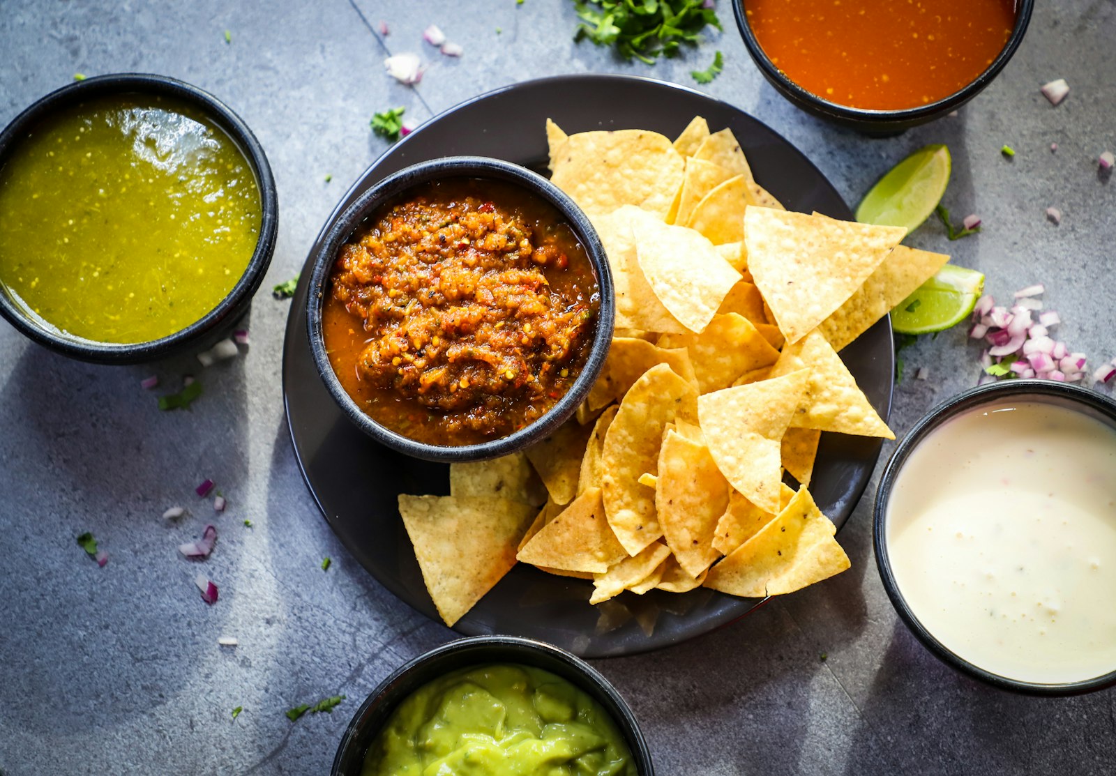 Bowls of salsa verde, salsa roja and guacamole with chips
