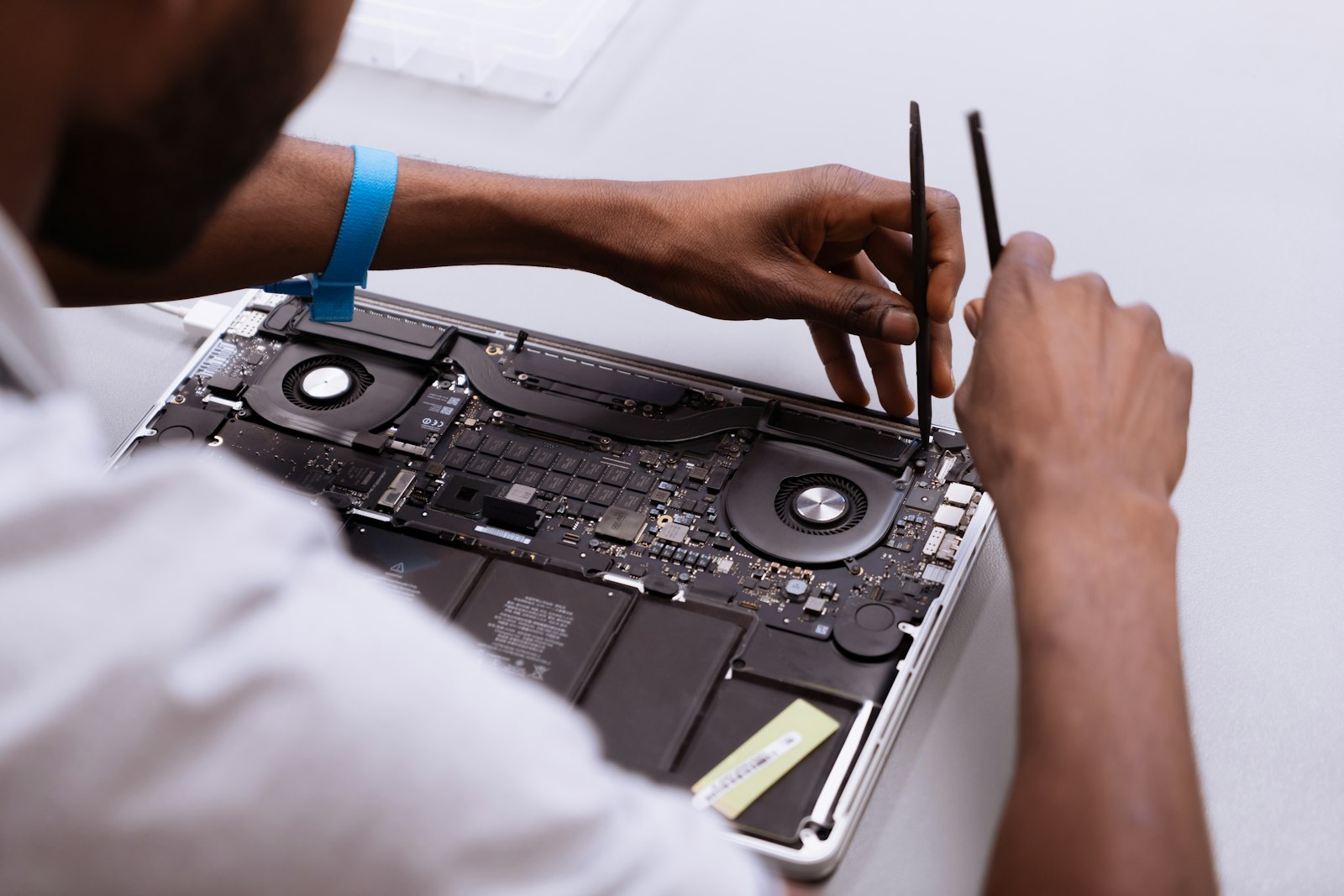 A technician using fine tools on an opened laptop