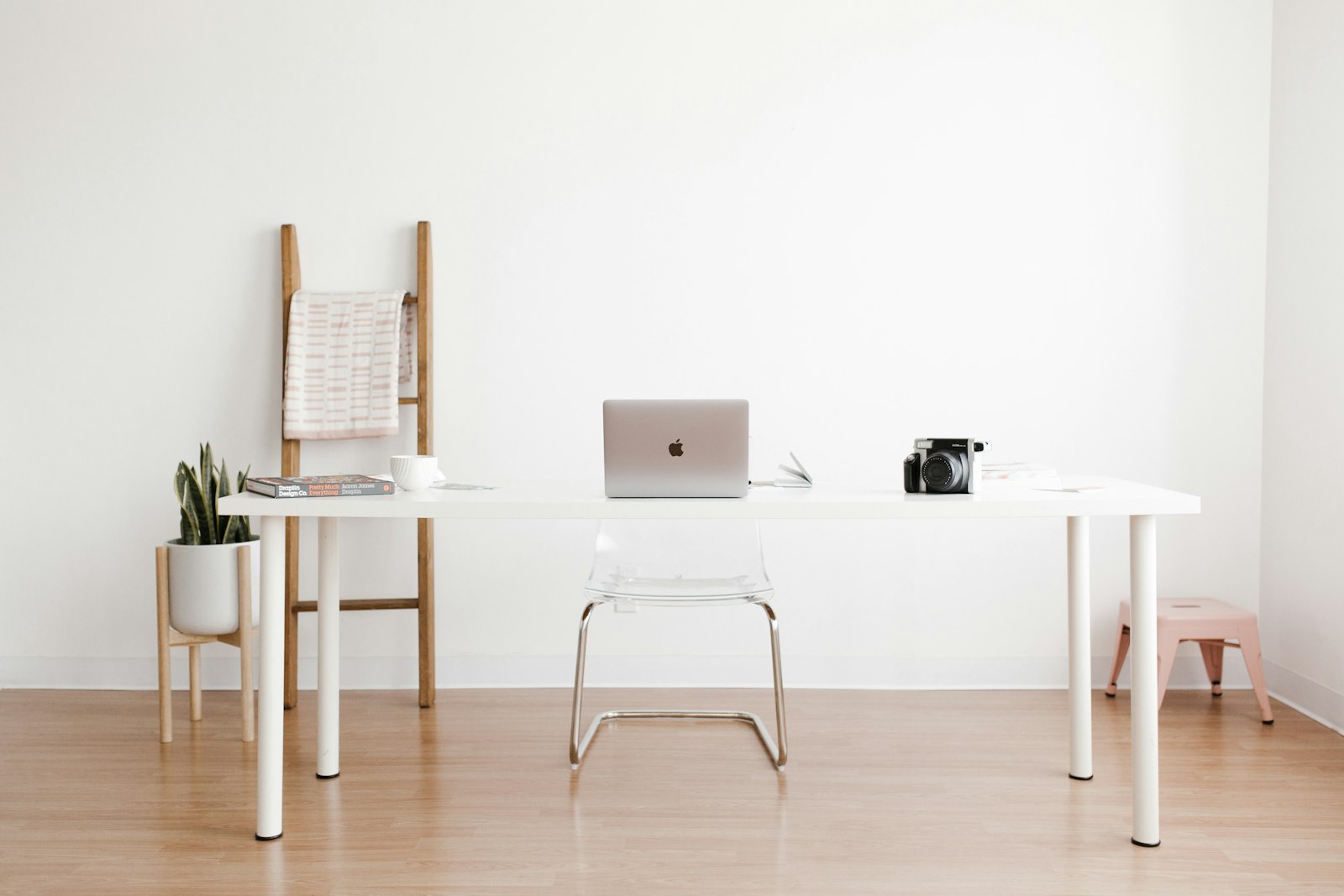 A fixed desk: a white table, a monitor and a chair by the window