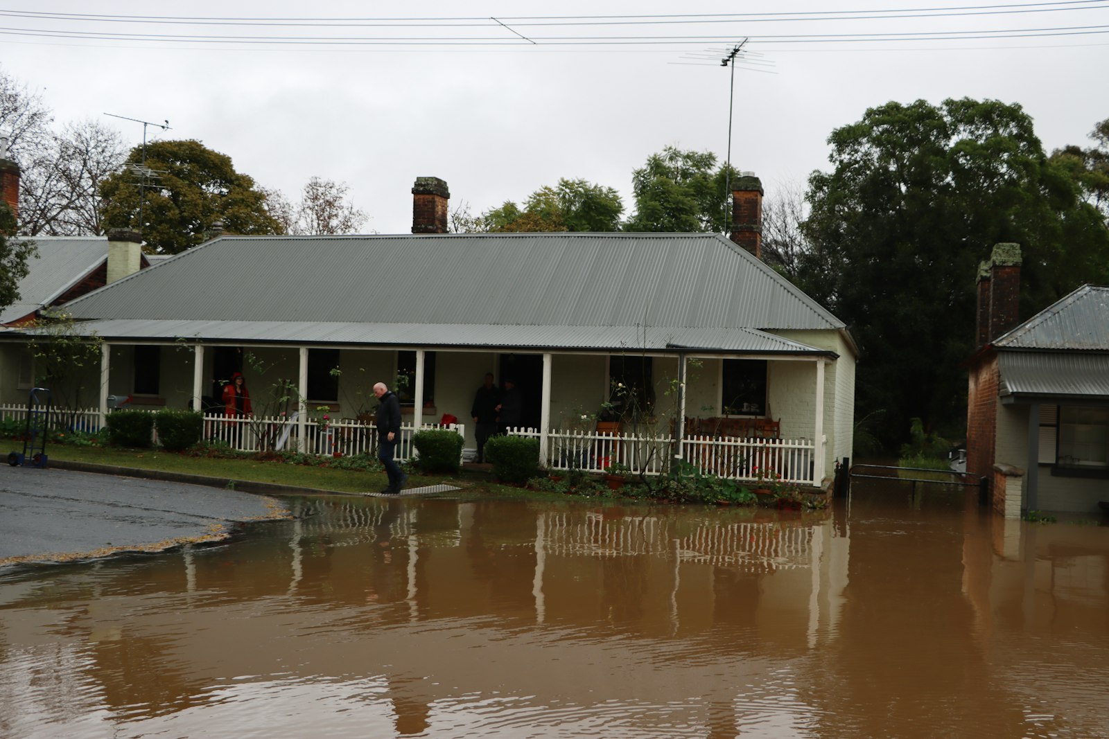 A house with a veranda and the street in front under floodwater