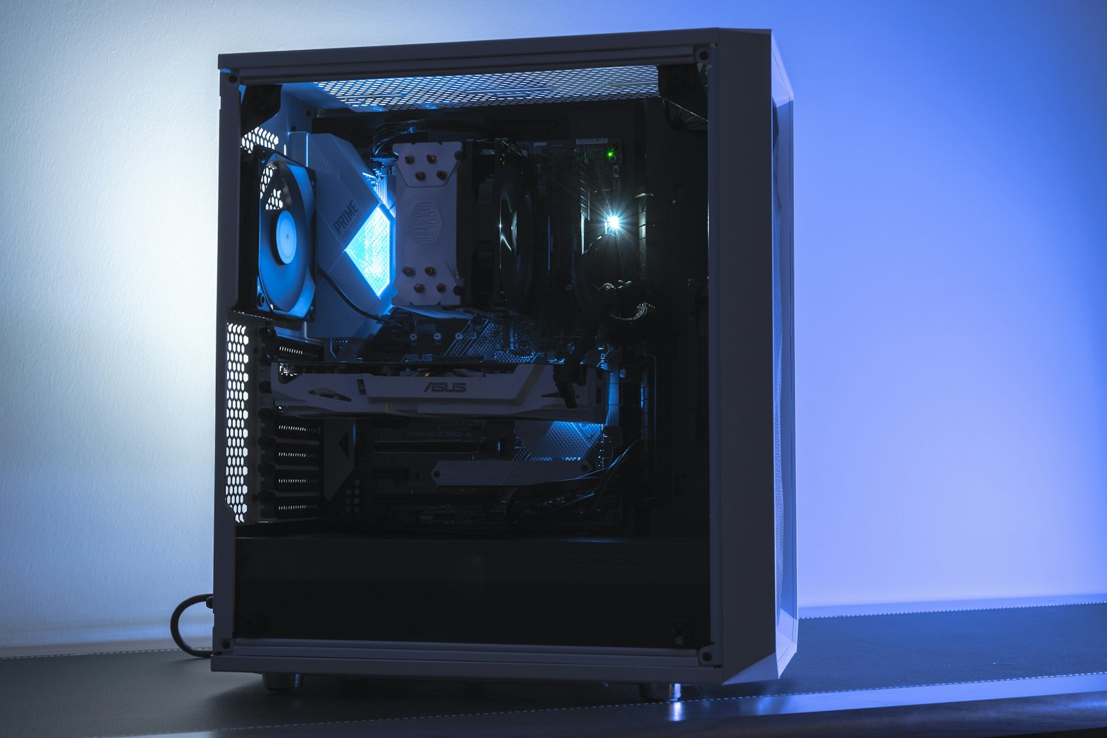 A custom PC tower with a glass side panel lit blue in a dark room
