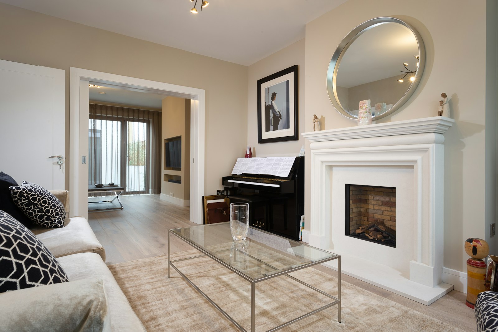 A show-home lounge with a white fireplace and a piano