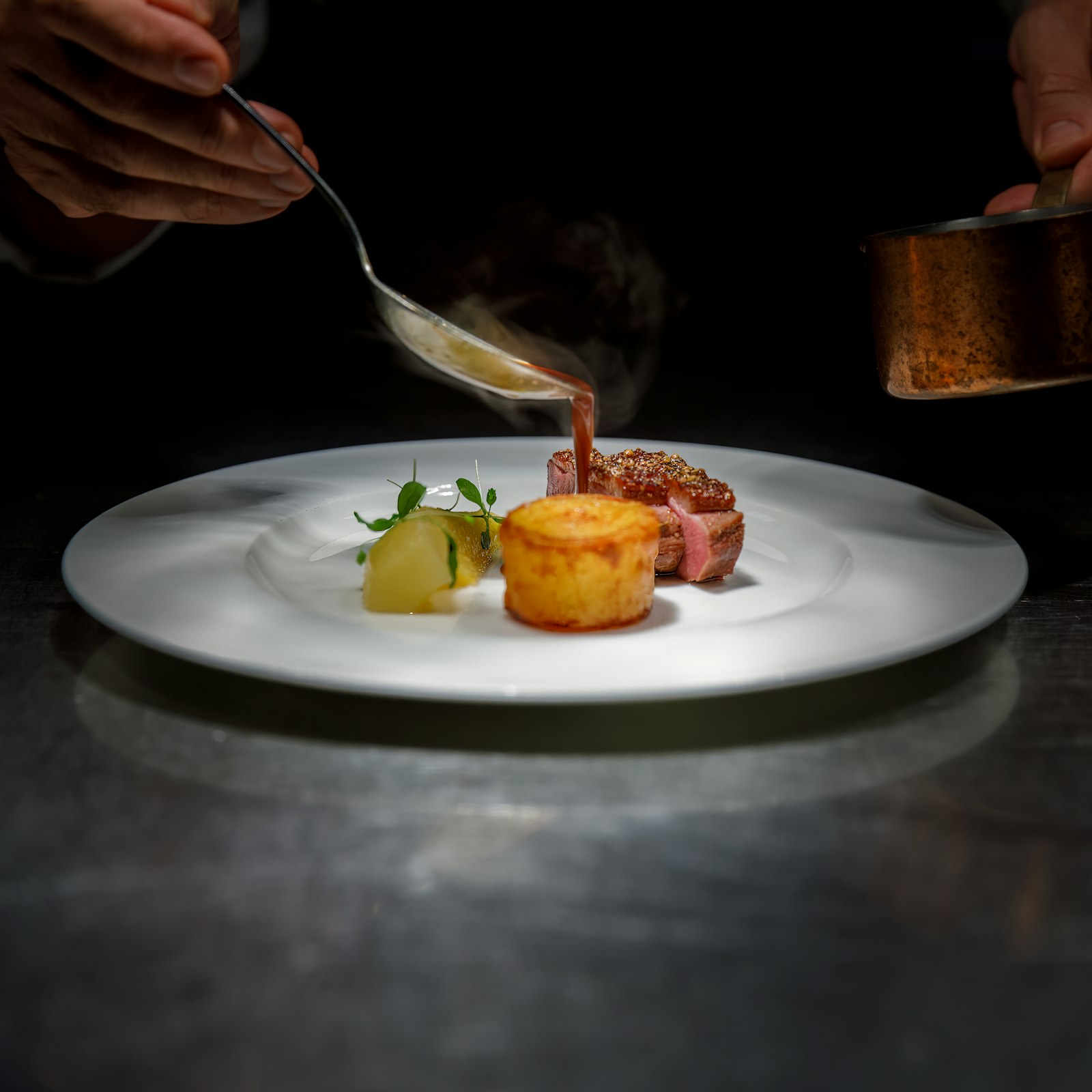 A chef spooning sauce onto a plated dish