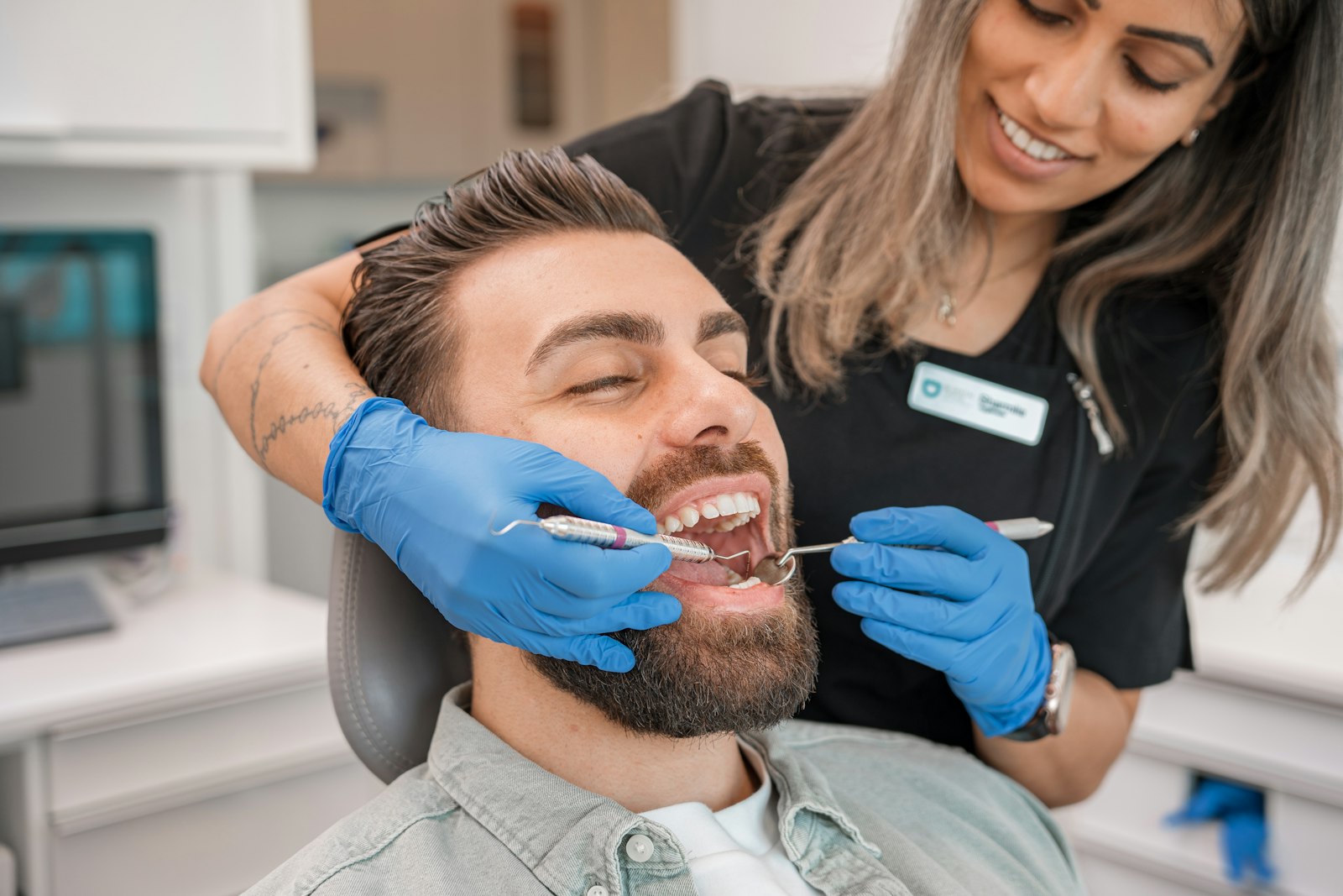 A dentist and a hygienist in blue gloves examining a patient in daylight