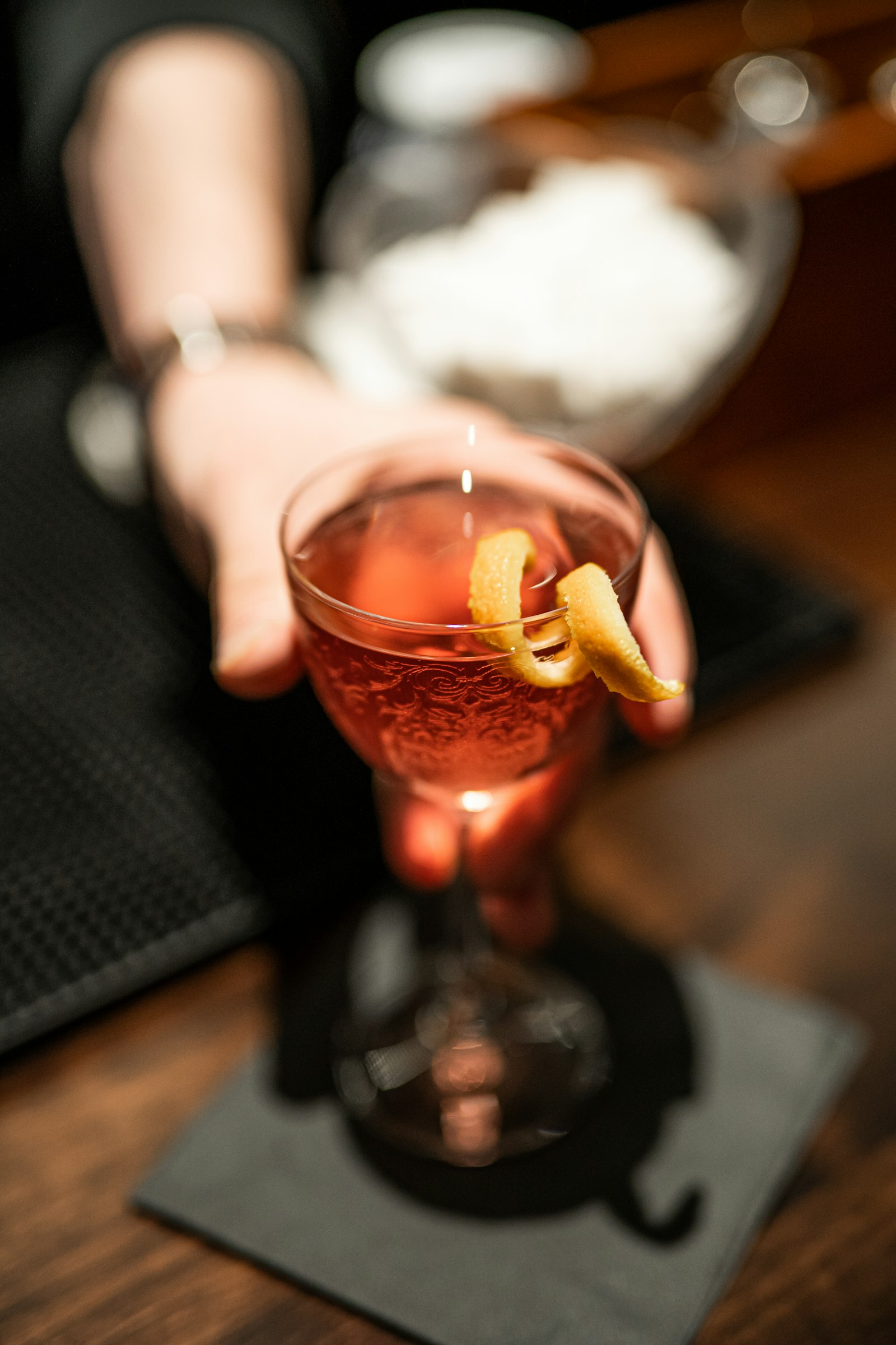 A pink cocktail with an orange twist