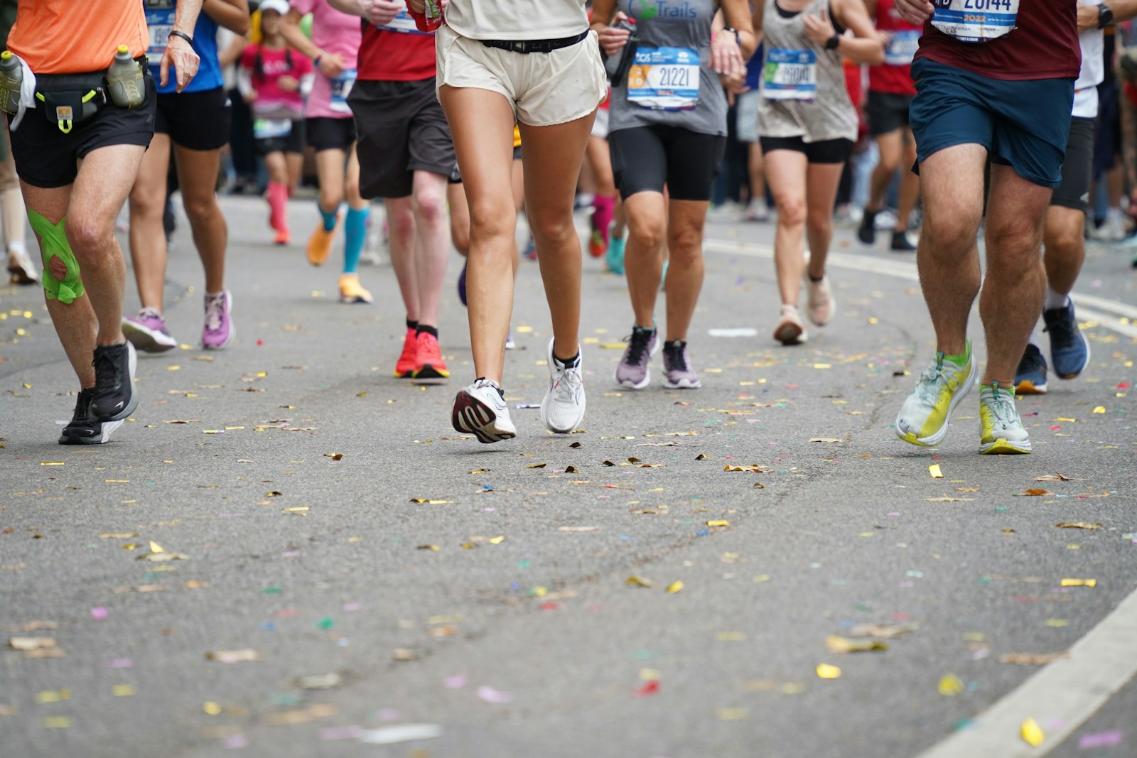 Runners' trainers on a confetti-strewn road