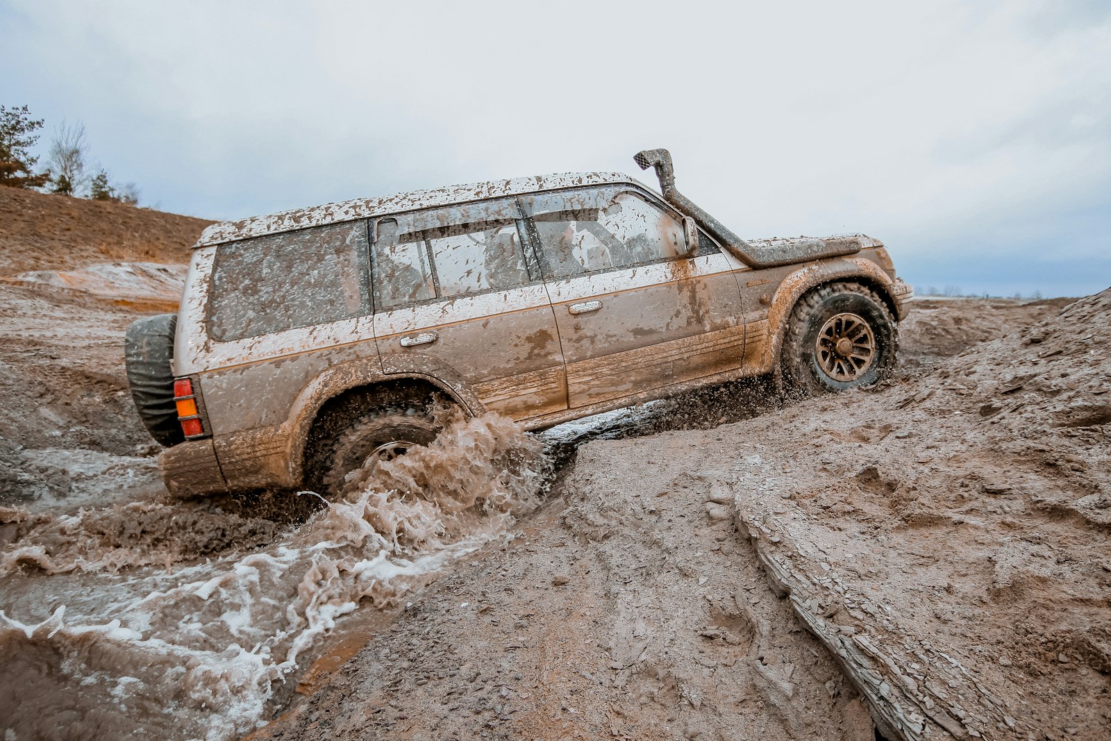 A mud-caked 4x4 ploughing through a muddy track