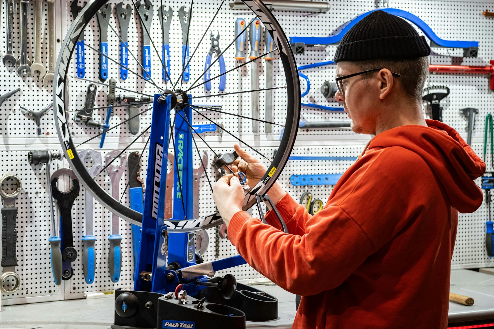A mechanic truing a wheel on a workshop stand
