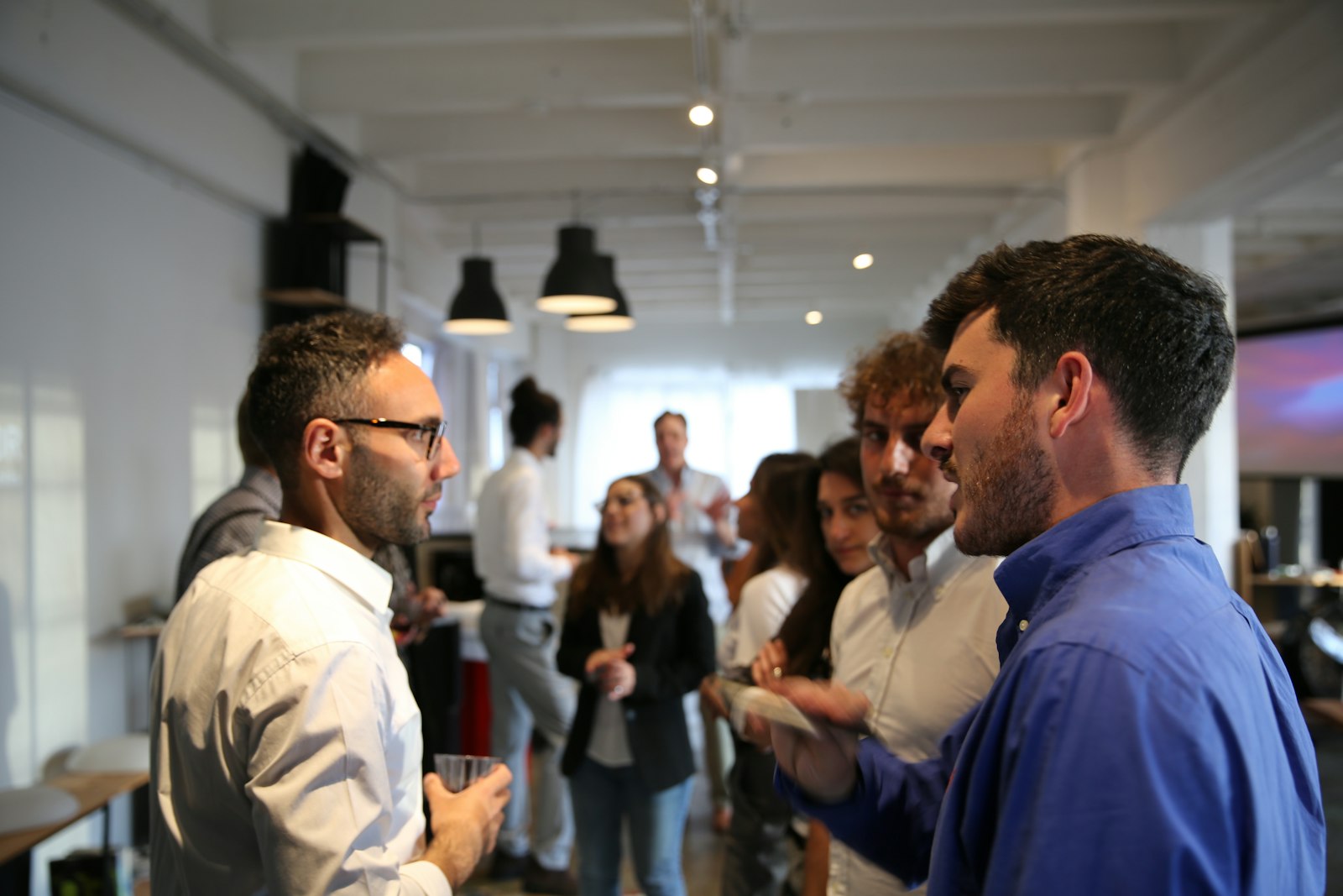 Attendees talking in small groups in a bright loft venue