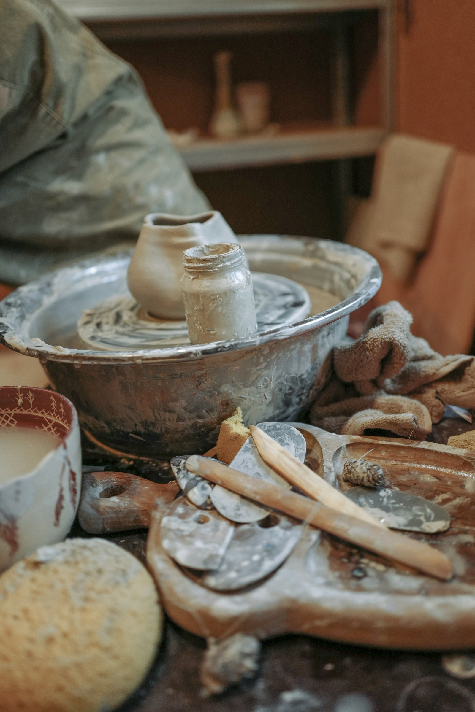 A slip-covered wheel with a small pot and trimming tools