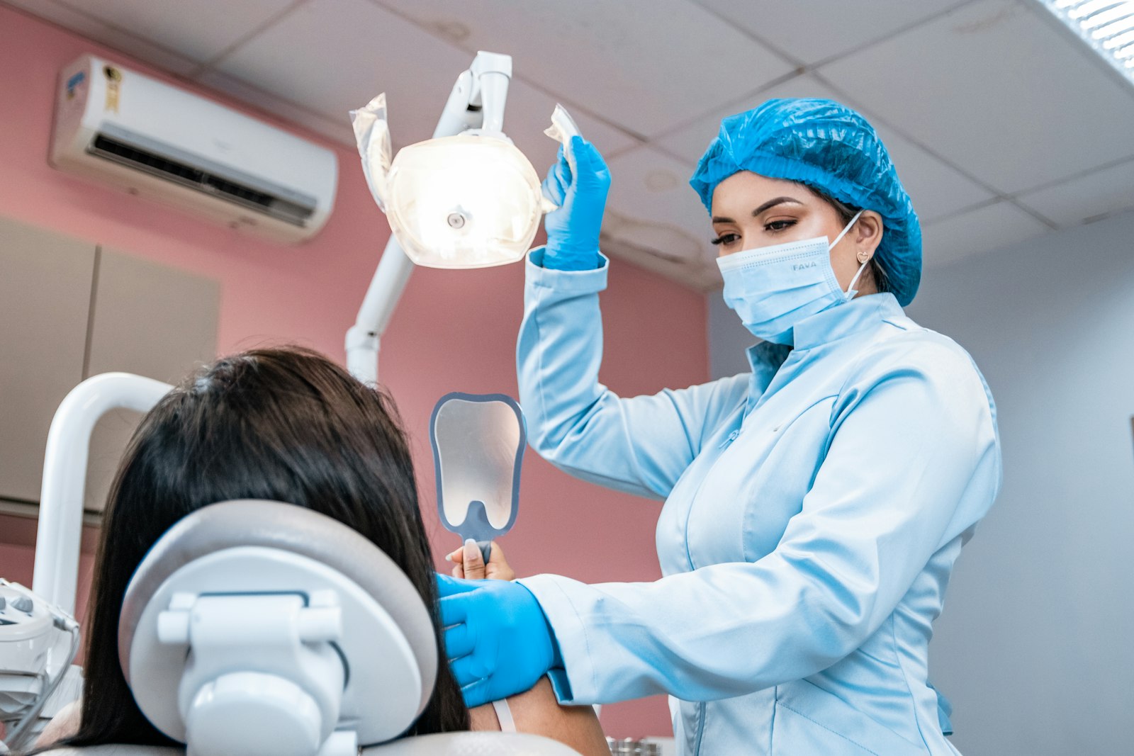 A woman having her teeth checked in a pink-walled surgery