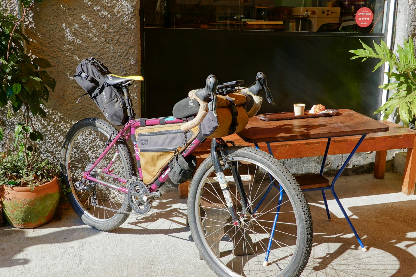 A touring bike leaning on a cafe table in the sun