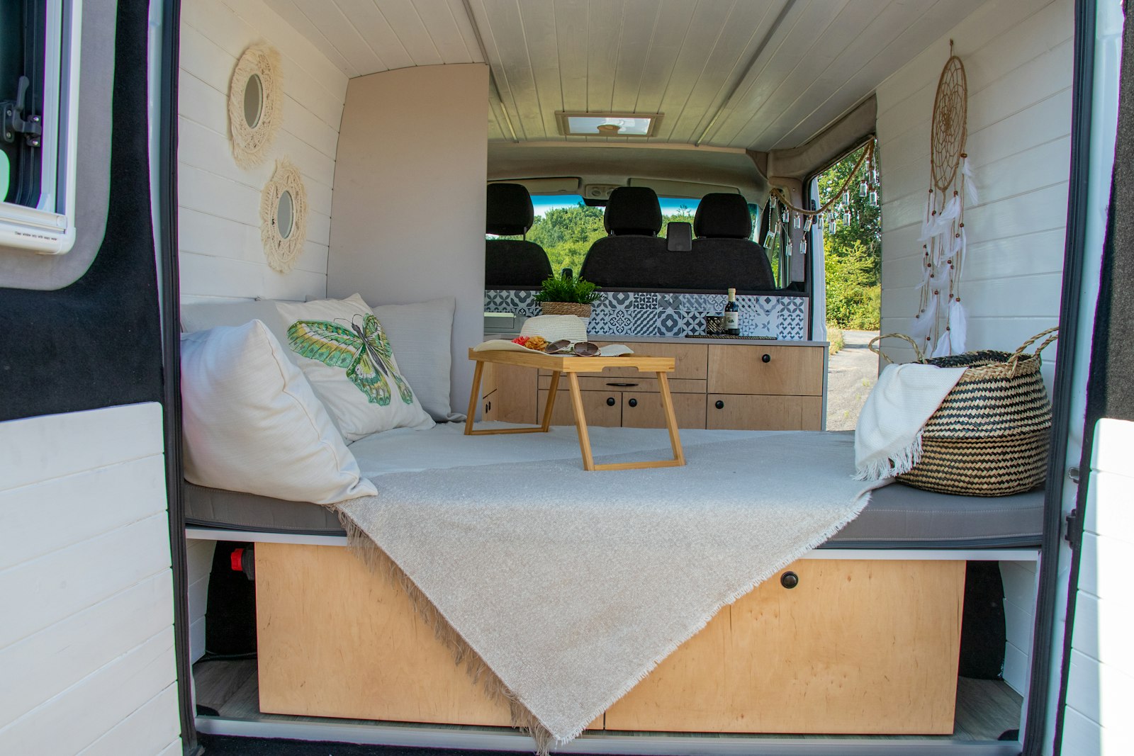 A converted van interior with a bench bed, table and cabinets