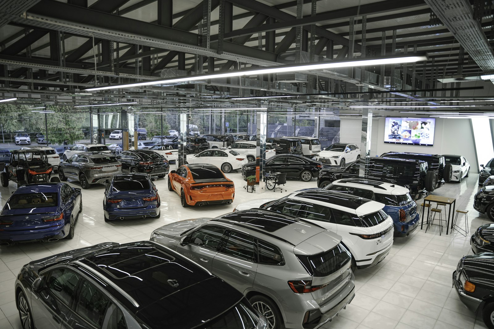 An indoor dealership floor of used cars under strip lights