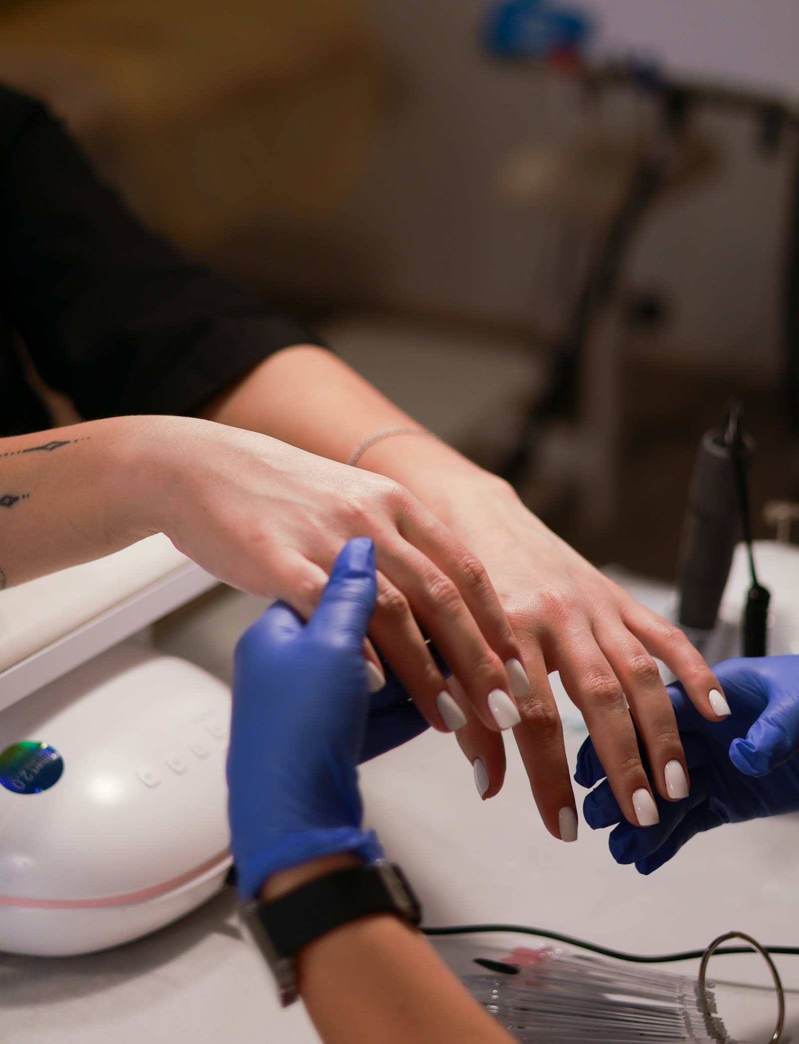 Freshly finished milky white gel nails beside a curing lamp
