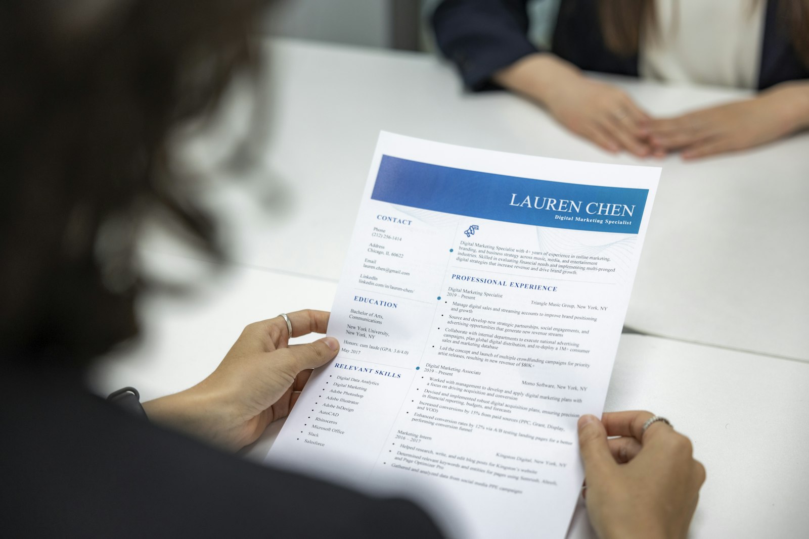 Hands holding a printed CV across an interview table