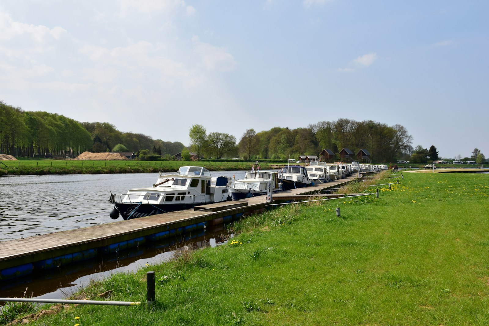 A row of white day boats moored at a riverside pontoon