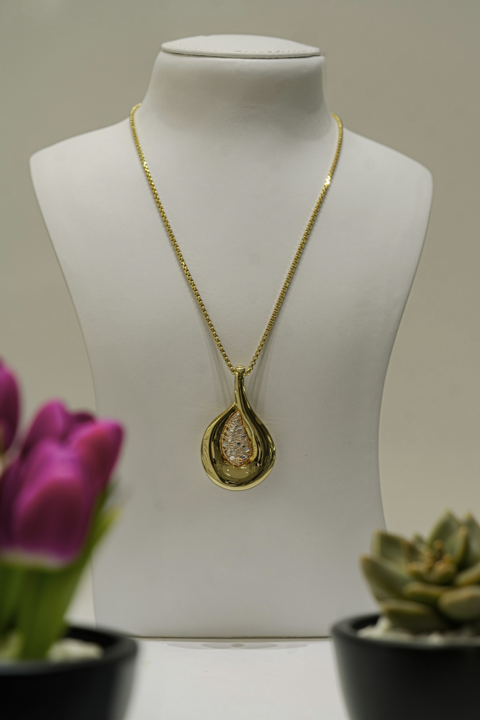 A gold pendant on a bust with a tulip